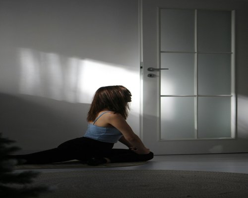 A person stretching lightly at home during the evening