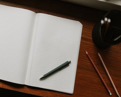 Notebook with a pen resting on a wooden desk